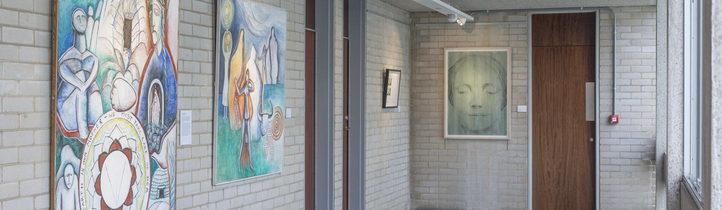 A photo of 4 artworks of varying sizes on a brick wall in a long corridor