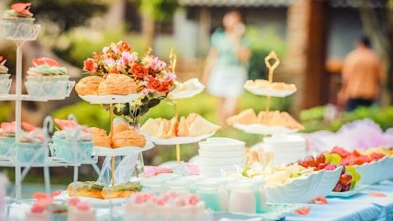 tea, cakes, sandwiches and flowers arranged on a table in a beautiful garden.