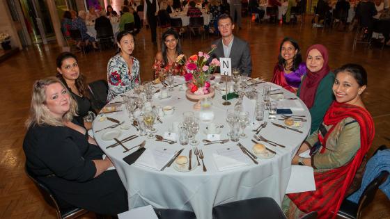 Group of event attendees sitting at a round table having dinner.